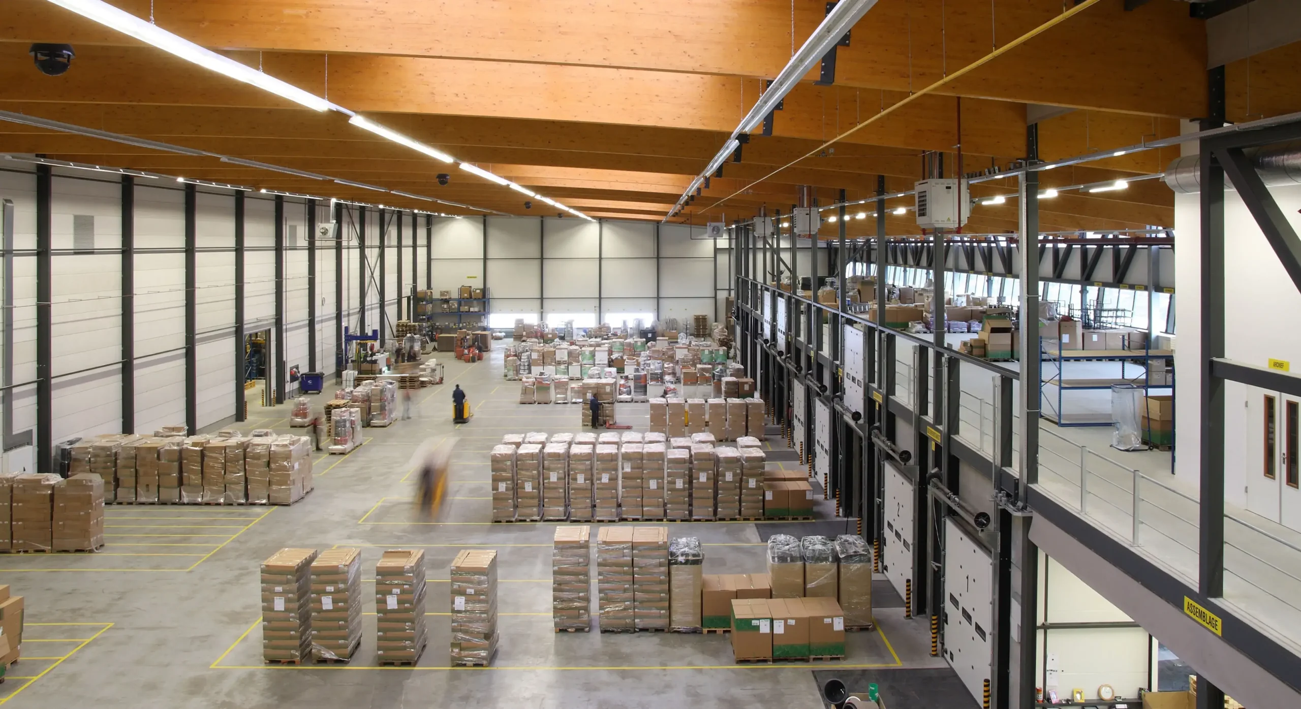 Overview of a spacious warehouse with pallets and boxes organized in rows.