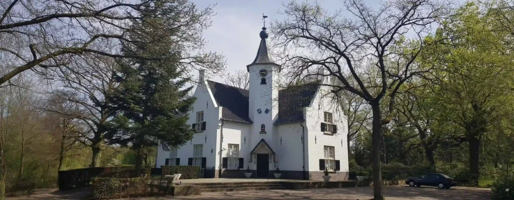 A historic white church surrounded by trees on a sunny day.