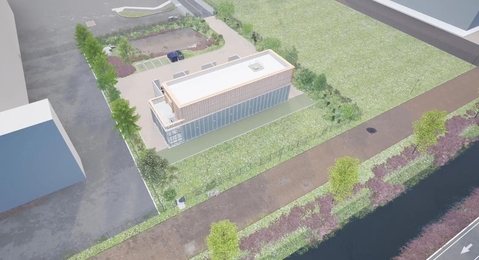Luchtfoto van een modern gebouw met een plat dak, omringd door grasvelden en bomen, gezien vanuit het noordoosten.