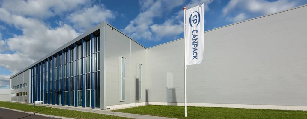 Front view of the modern CanPack industrial building with a flag displaying the company logo.