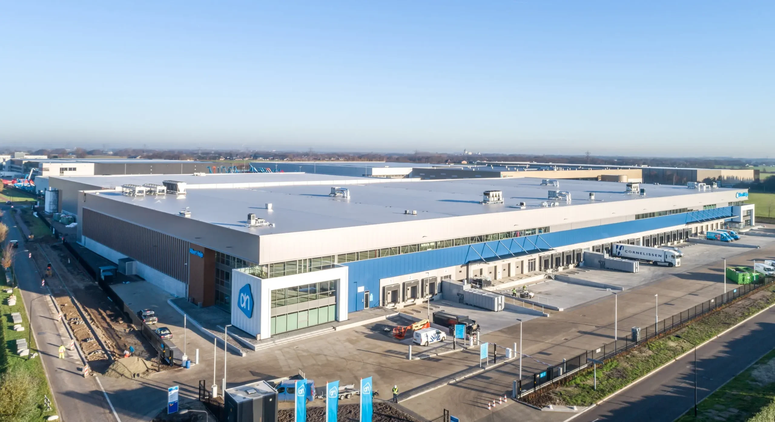 Aerial view of the Albert Heijn distribution center with several delivery trucks stationed outside.
