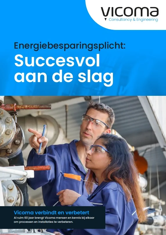 Twee ingenieurs in blauwe werkkleding bespreken een installatie in een industriegebouw.