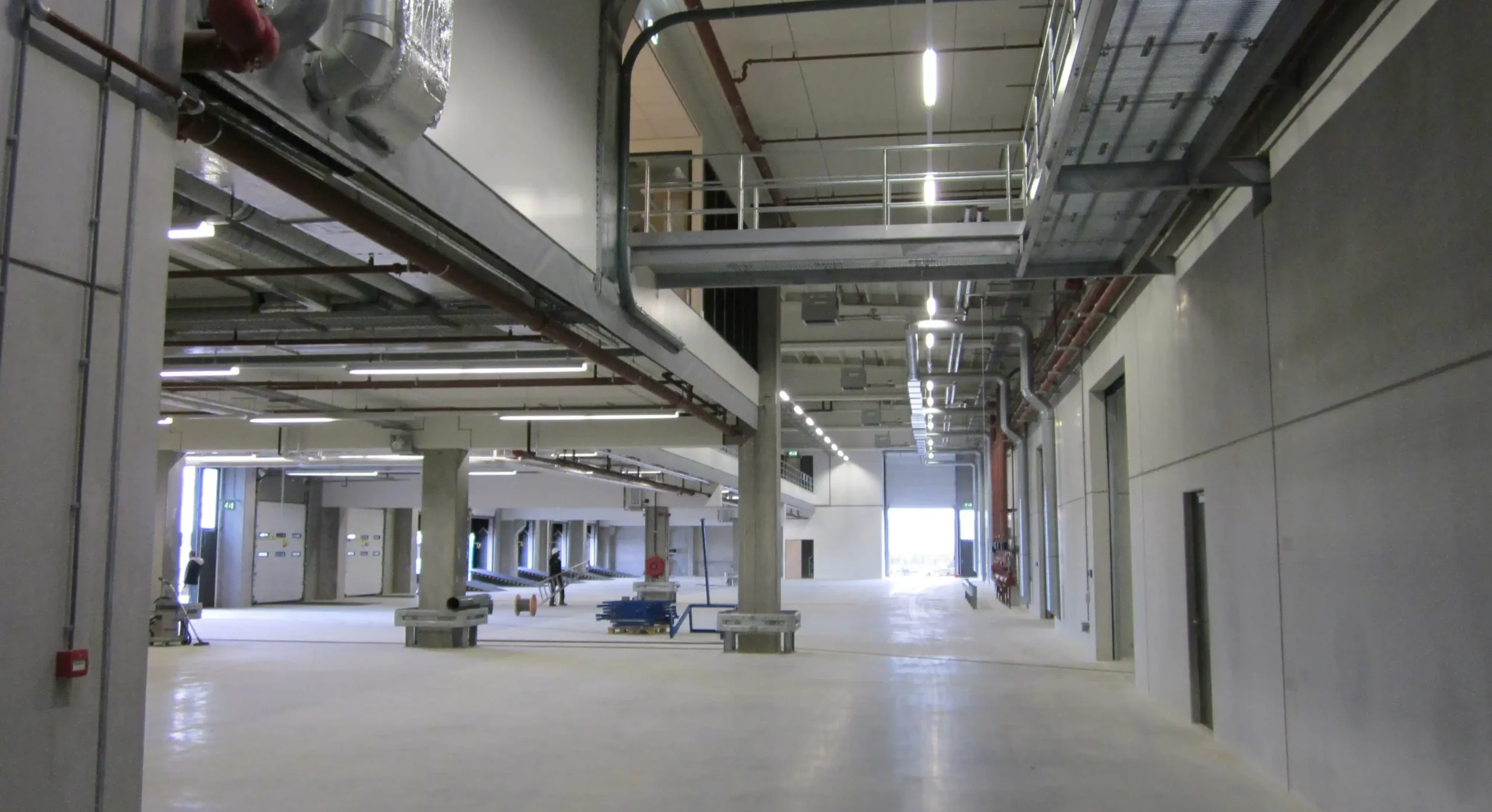 A spacious industrial interior with exposed pipes and large overhead structures.