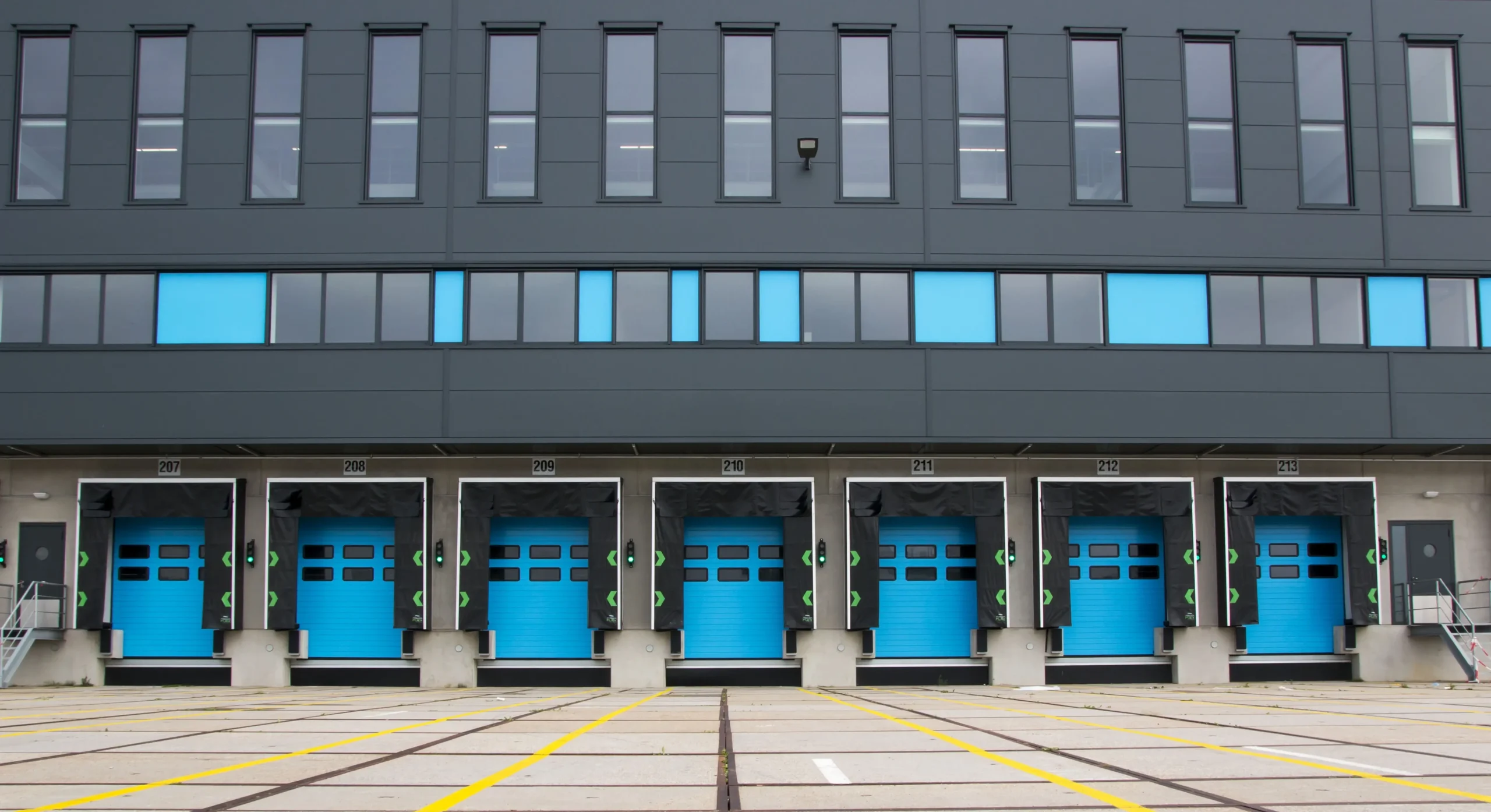 A row of blue industrial loading dock doors at a modern warehouse facility.