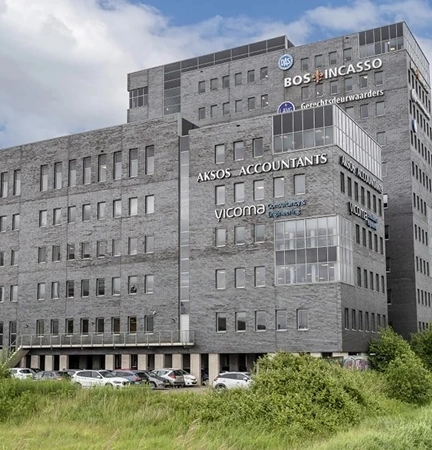 A modern office building in Groningen featuring company signage, including Vicoma.