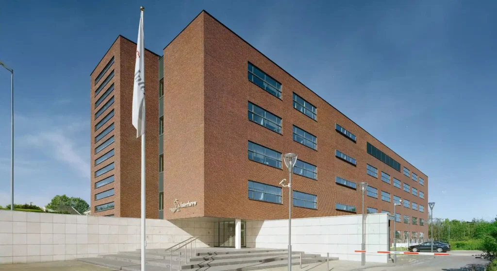 A modern brick office building with the Interbrew logo in Breda, featuring large windows and a flagpole.