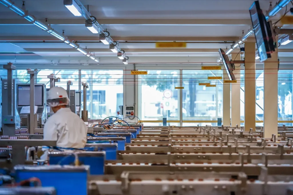 A worker in a white uniform and helmet operates machinery in a factory setting.