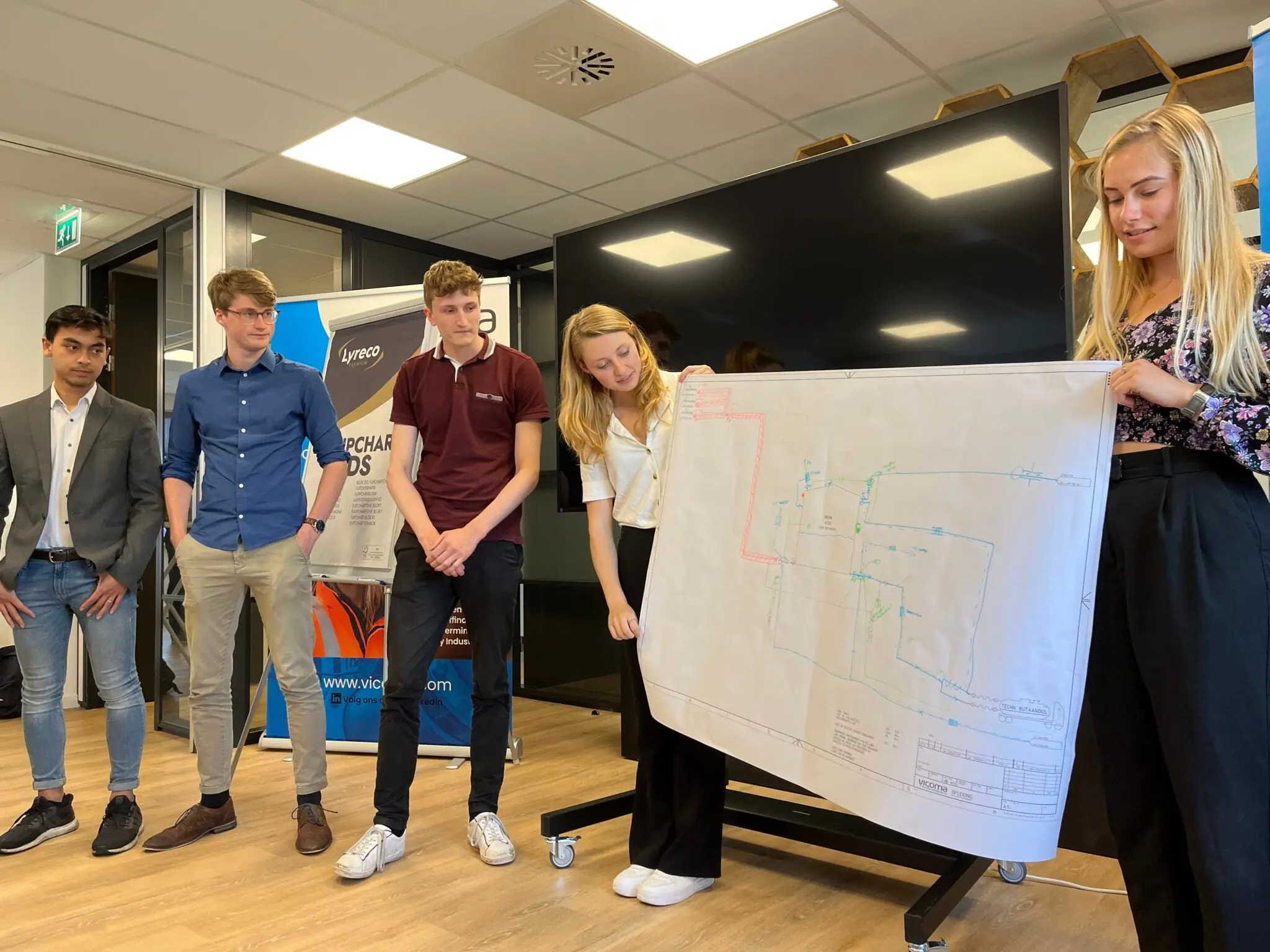 Studenten van studievereniging Lugus presenteren een technische tekening tijdens een bijeenkomst.